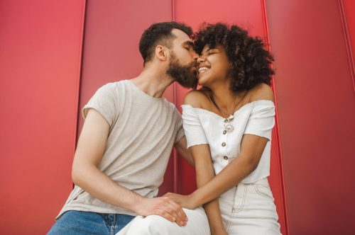 Woman smiling while man kisses her on the cheek
