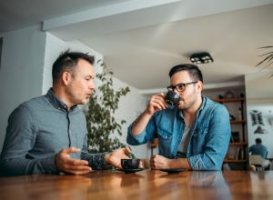 Two casual businessmen talking and drinking coffee at workplace