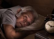 A depressed senior man lying in bed cannot sleep from insomnia