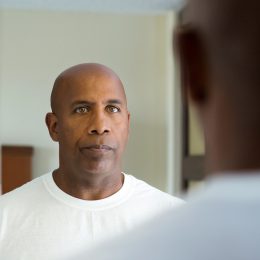 middle aged bald man looking in mirror