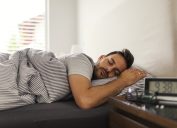 Handsome man sleeping in his bedroom. Man sleeping with alarm clock in foreground.