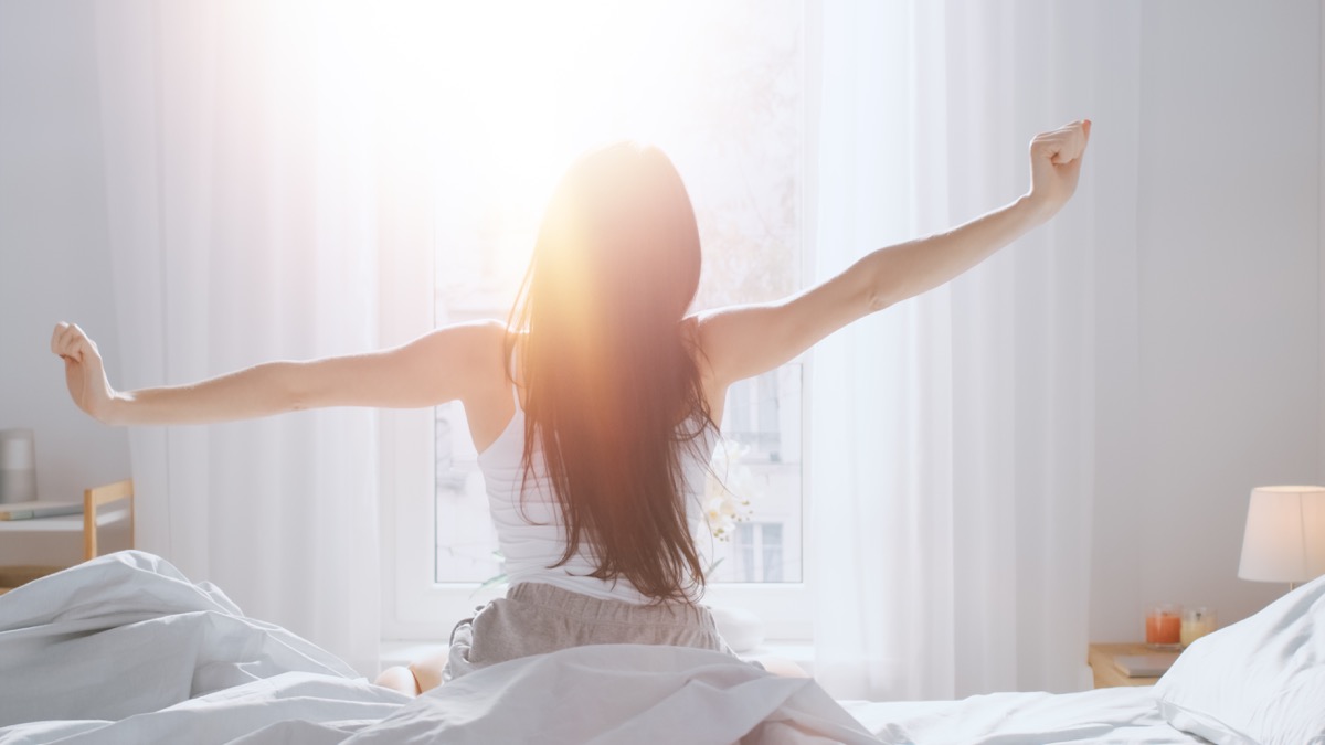 Woman stretching in bed in the morning