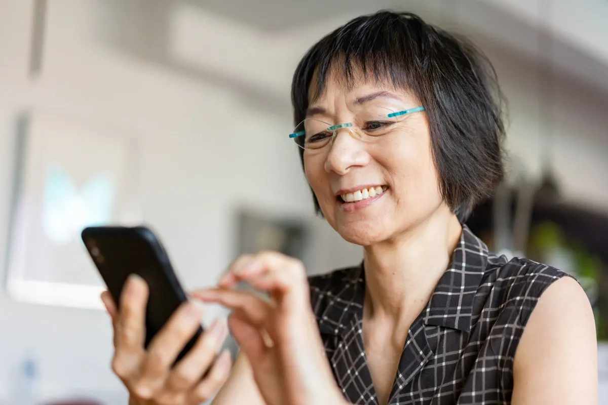Senior woman smiling when using a smartphone.