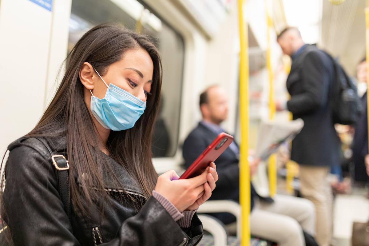 Young woman wearing a face mask while travelling by tube to protect from coronavirus