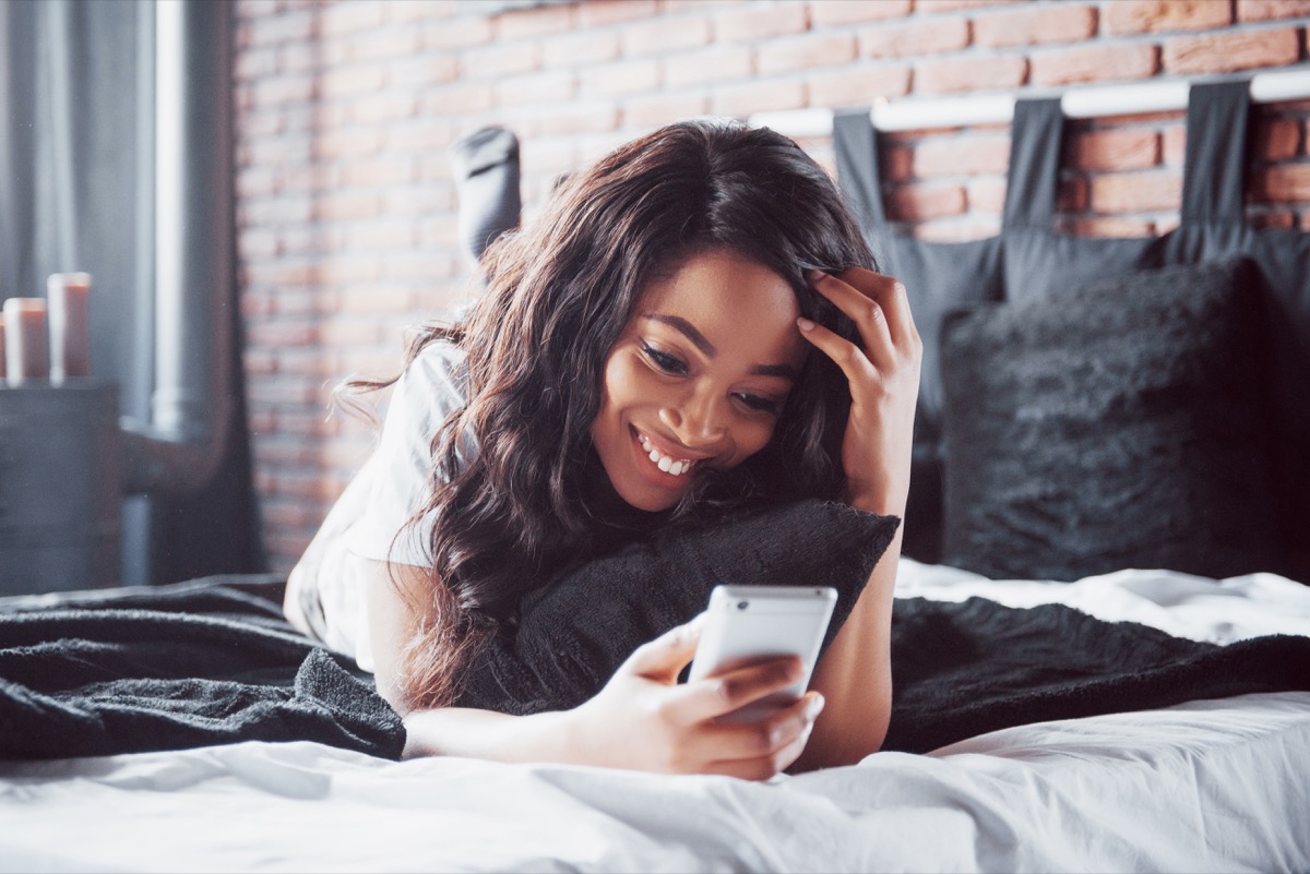 Woman using a dating app while laying on her bed