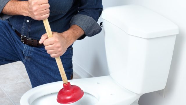 white plumber plunging toilet