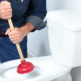 white plumber plunging toilet