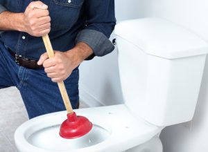 white plumber plunging toilet