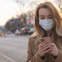 woman with a face mask looking at her phone outside