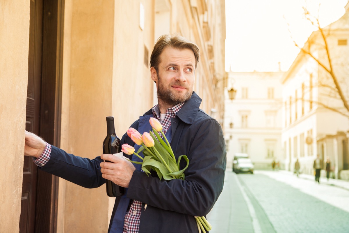 middle aged man carrying flowers and wine