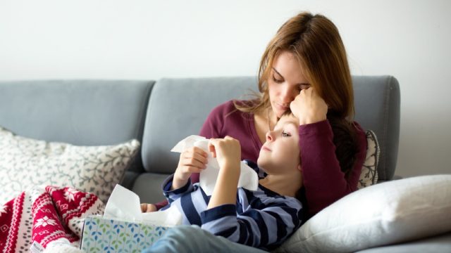 white mother holding sick son on couch