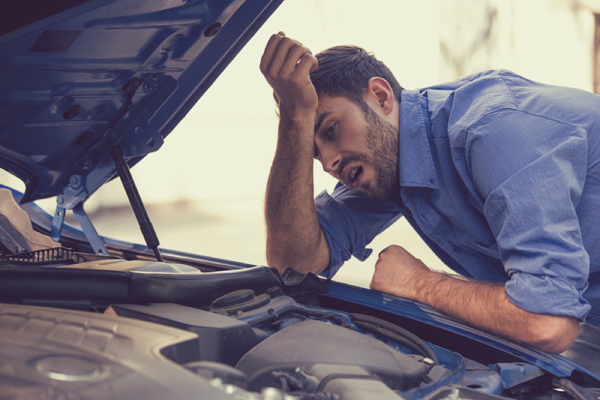 white man bending over the engine of a car