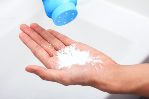 hand with baby powder, blue bottle visible above