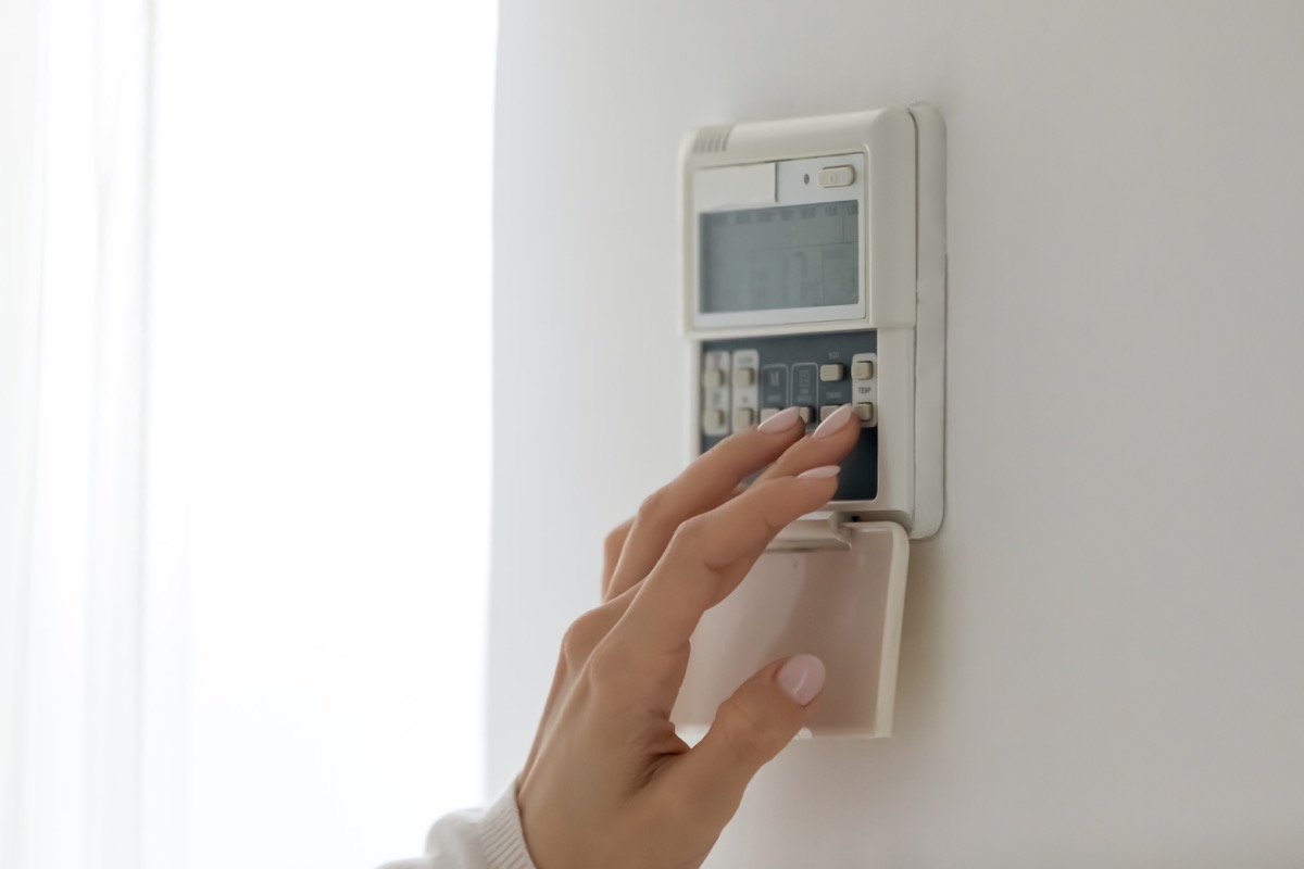 Woman changing thermostat temperature