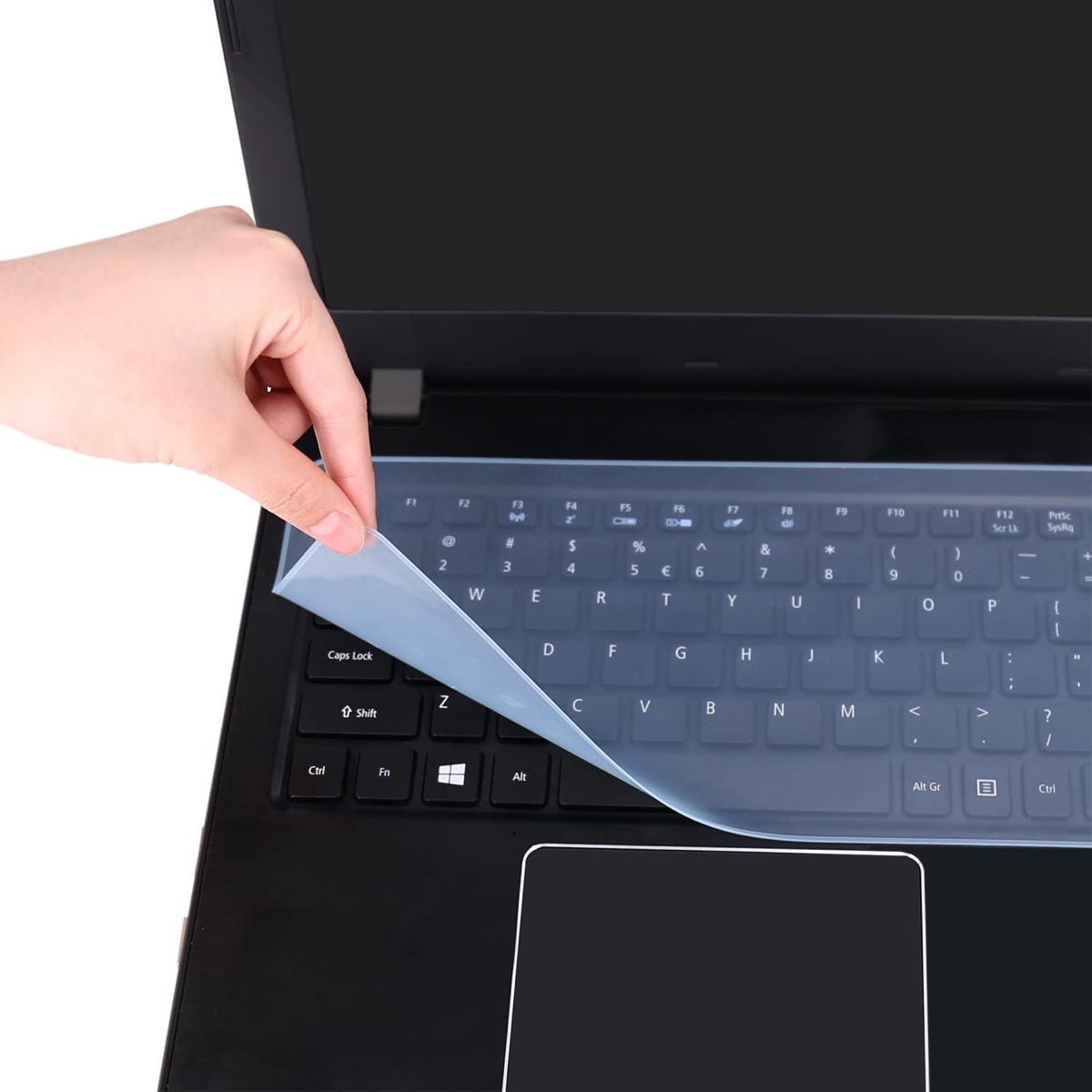 white hand peeling clear protector off black laptop