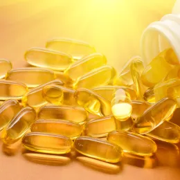 close up of vitamin d capsules spilling out of bottle with sunshine lighting them up