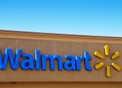 A blue Walmart sign and corporate logo on the front of a brown store.