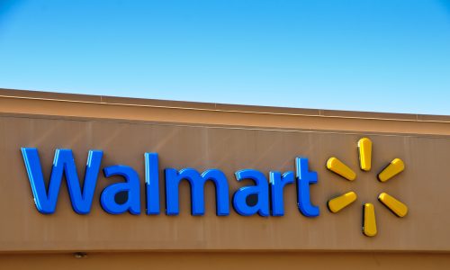 A blue Walmart sign and corporate logo on the front of a brown store.
