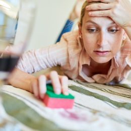 white woman looking annoyed while cleaning fabric with a sponge