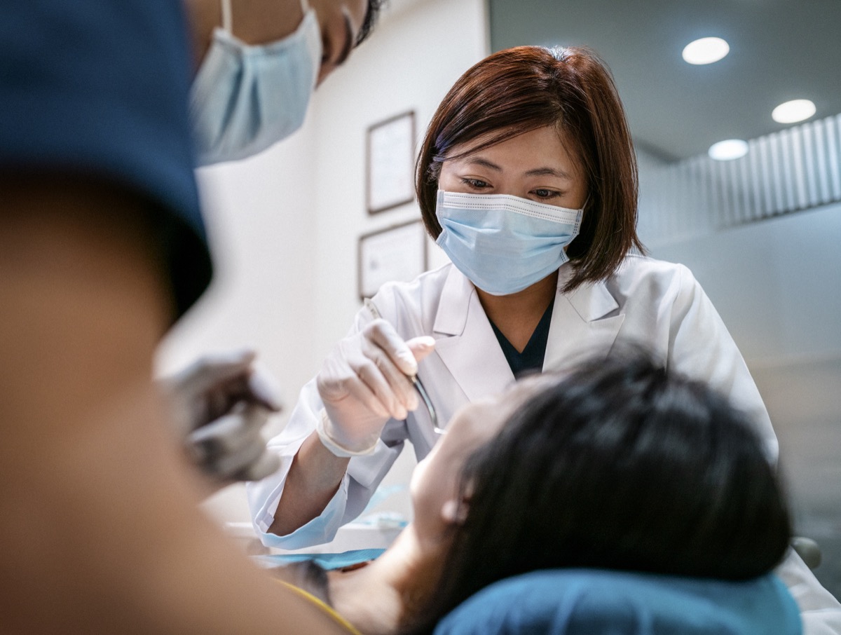Dentist with male assistant treating female patient