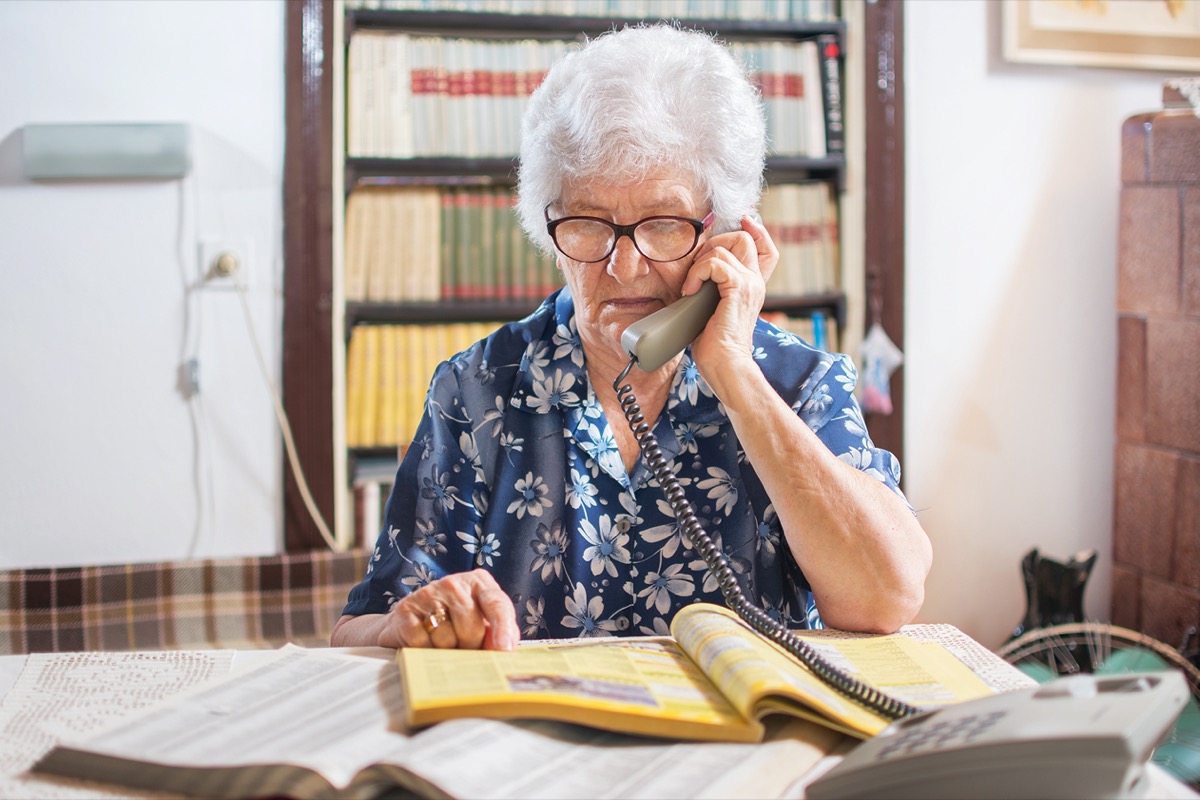 senior woman calling from a yellow phone book