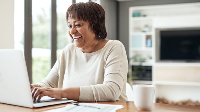 Cropped shot of a happy senior woman sitting alone and using a laptop in her living room at home
