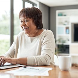 Cropped shot of a happy senior woman sitting alone and using a laptop in her living room at home