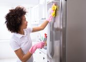 Woman cleaning fridge with gloves