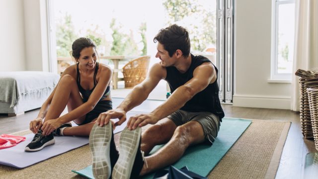 A young couple exercising together on yoga mats in their living room.