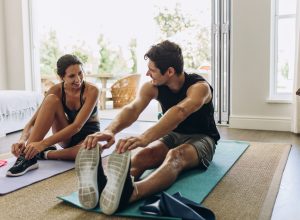 A young couple exercising together on yoga mats in their living room.