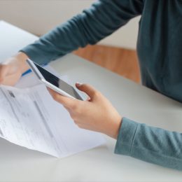 young white woman looking at cell phone bill