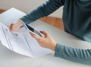 young white woman looking at cell phone bill