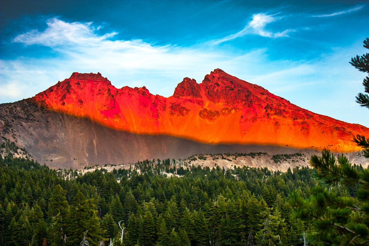 red stratovolcano and green trees in Broken Top, Oregon at sunset