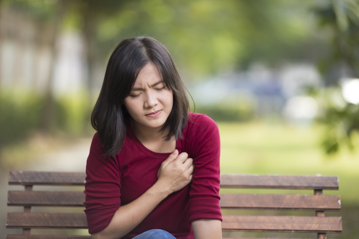 Woman with chest pain siting outside on bench