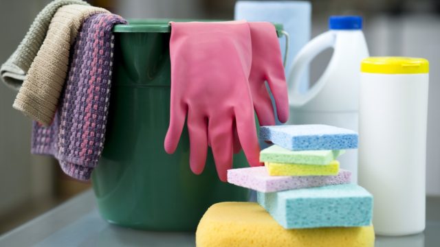 Bucket, sponges, gloves, disinfectant wipes and Protective face masks on desk in preparation to clean offices and furnishings.