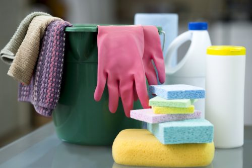 Bucket, sponges, gloves, disinfectant wipes and Protective face masks on desk in preparation to clean offices and furnishings.