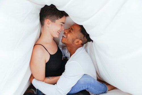 Paar flirtet unter Bettdecke