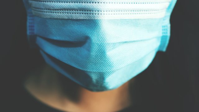 closeup of person wearing blue surgical mask to protect against Covid-19