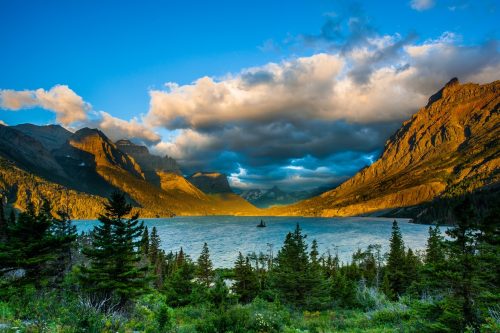 dark yellow mountains and trees next to St. Mary Lake at Glacier National Park in Montana at sunrise