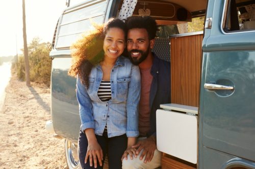 Glückliches junges schwarzes heterosexuelles Paar, das in einem Lieferwagen sitzt