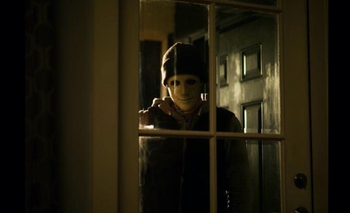 man wearing creepy mask standing outdoors in Hush