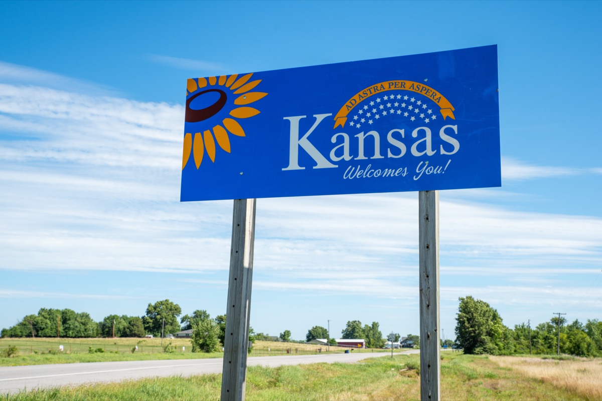 a blue "Kansas Welcomes You!" sign off of a highway