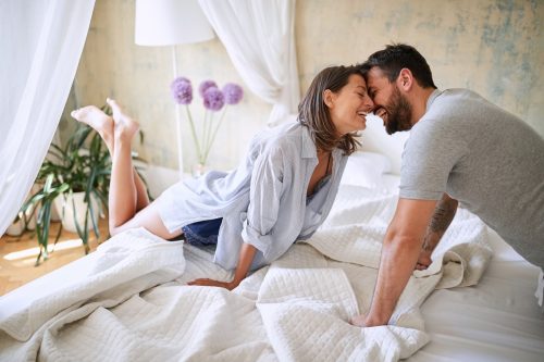 Couple flirting while making bed together