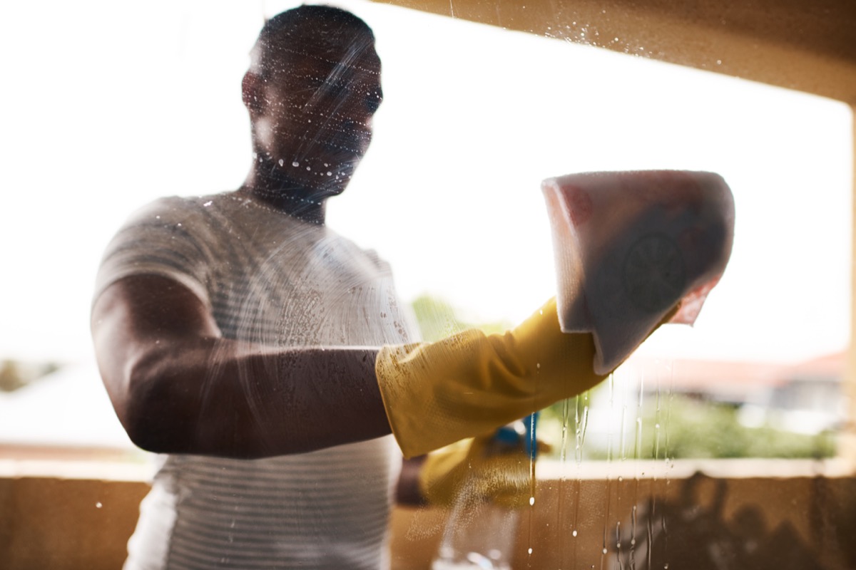 Cropped shot of a man washing his windows at home