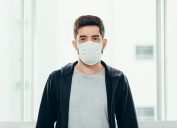 Portrait of man wearing surgical mask at home. Covid-19, coronavirus and quarantine concept.