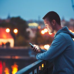 Man texting on balcony to cancel a date