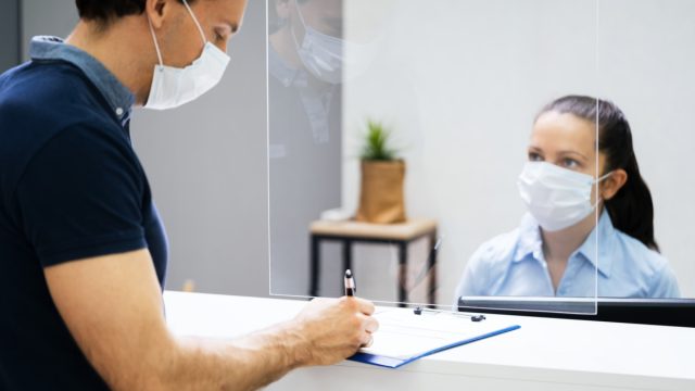man wearing mask signing paperwork at doctor or dentist