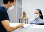 man wearing mask signing paperwork at doctor or dentist