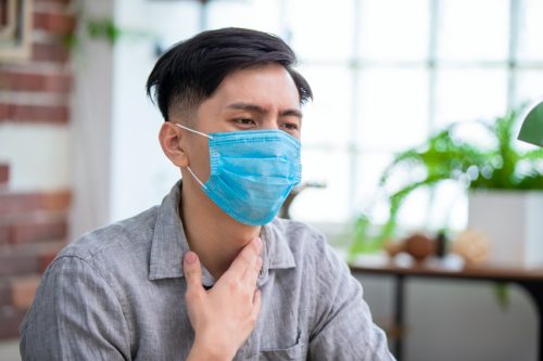 man has sore throat and wear face mask at home
