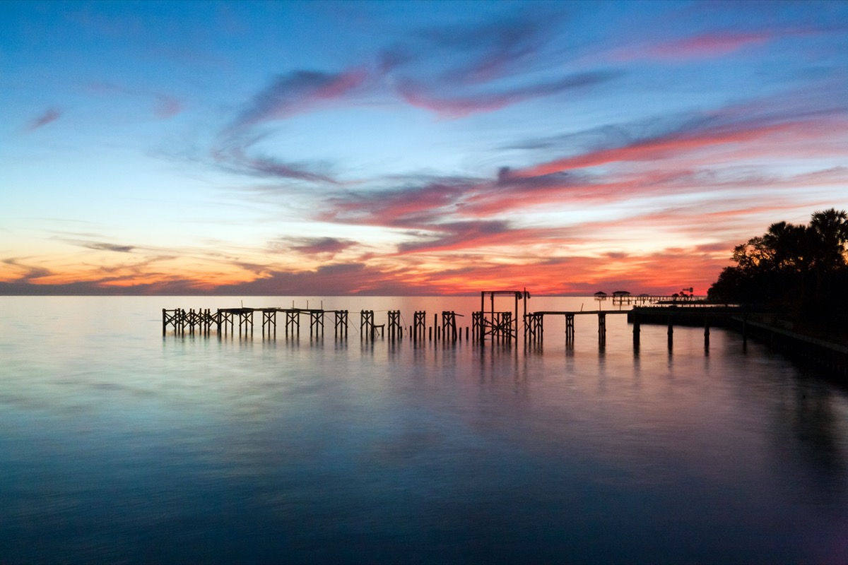 a pier over and trees next to Lake Pontchartrain in Mandeville Louisiana at sunset